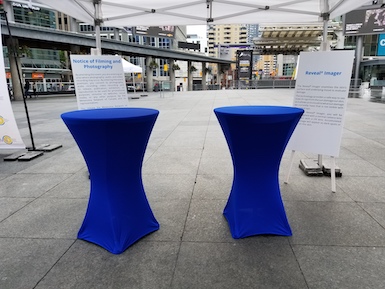 2 30 inch round cruiser tables with blue stretch tablecloths and marketing materials behind them at Dundas Square